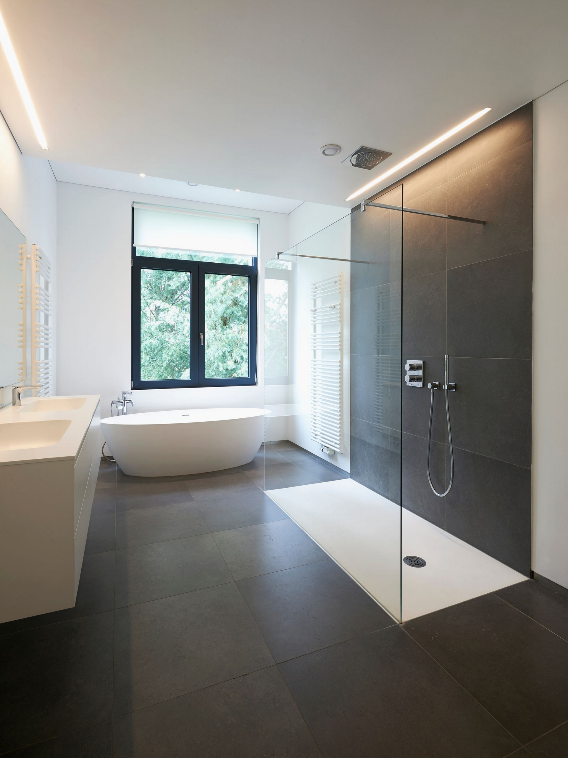 Salle de bains moderne avec sol foncé, douche, baignoire.