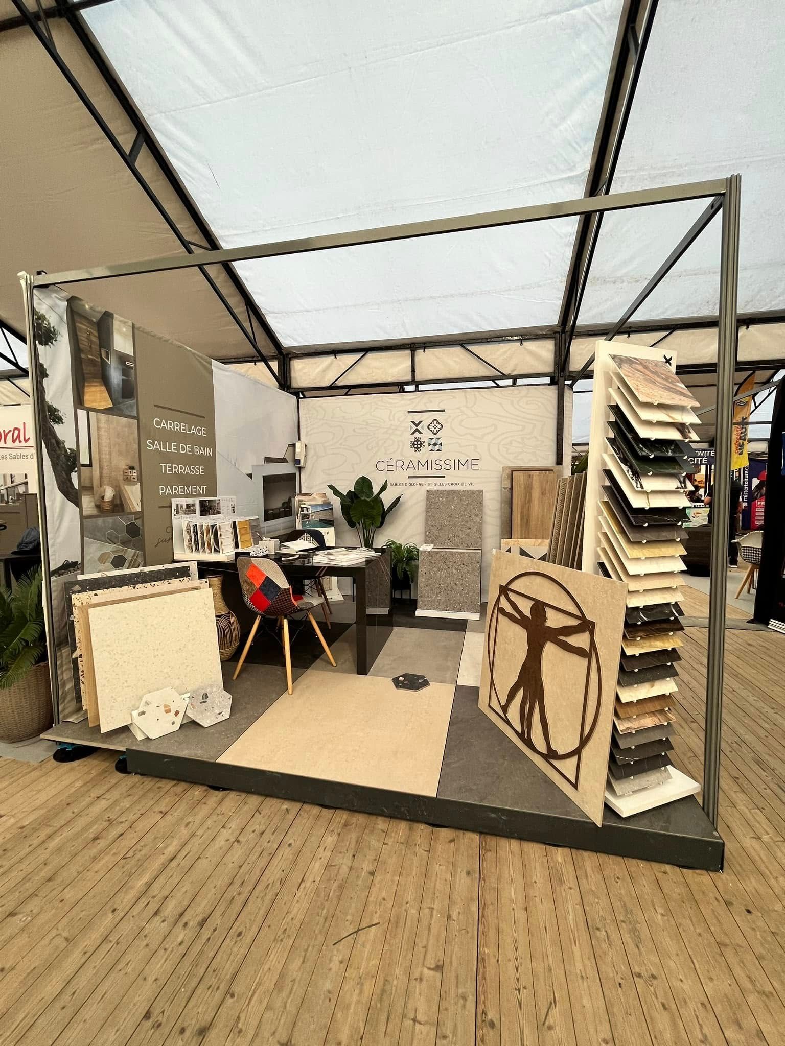 Un stand d'exposition présentant des échantillons de carrelage et de revêtements de sol, avec un motif d'Homme de Vitruve sur un panneau d'affichage.