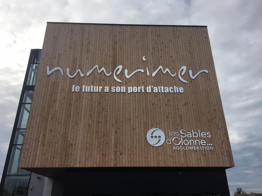 Deux voitures de société aux couleurs de la marque sont garées devant un bâtiment FMC Formacoupe, sur un terrain gravillonné, sous un ciel nuageux.