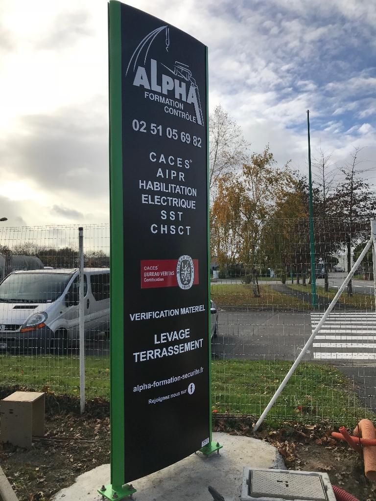 Une grande enseigne extérieure noire et verte faisant la publicité des services de formation professionnelle d'Alpha, située sur un parking.