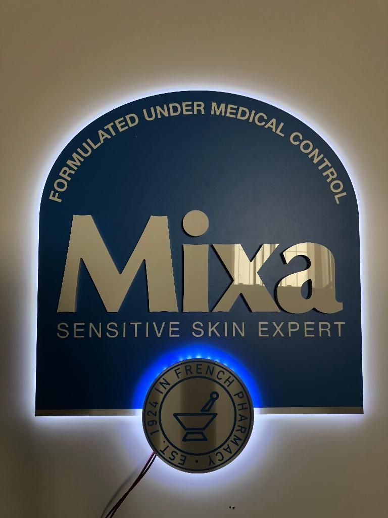 Une enseigne rétroéclairée de la marque Mixa est fixée au mur.