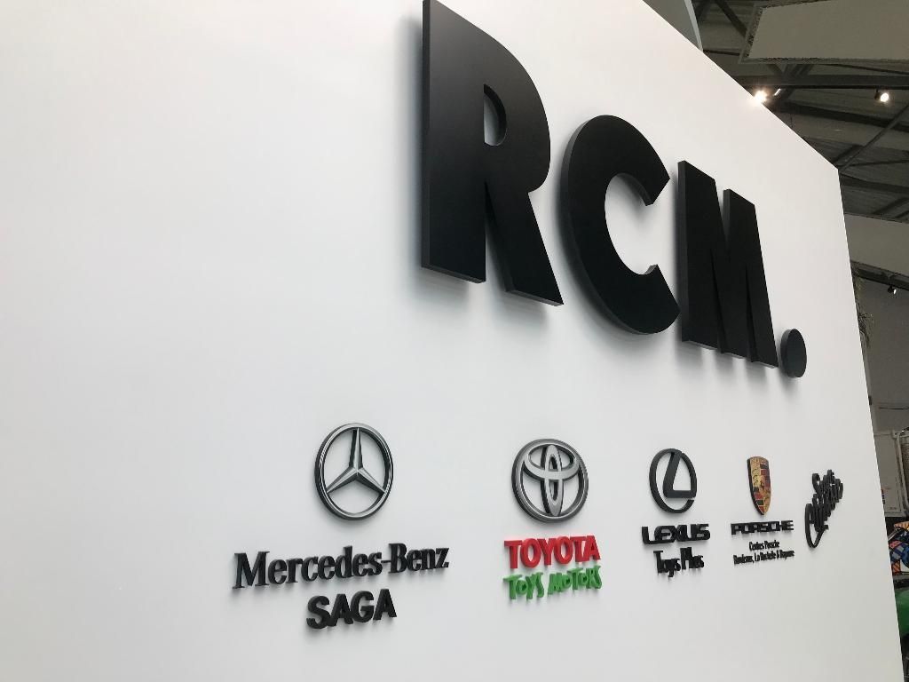 Mur blanc orné d'un grand logo noir RCM au-dessus des logos de Mercedes-Benz, Toyota, Lexus, Porsche et Saga Classic.