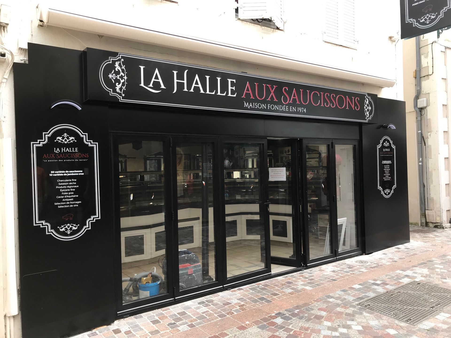 Le mot botanic en lettres blanches 3D, fixé sur une paroi vitrée, se détache sur un ciel bleu avec quelques plantes vertes en contrebas.