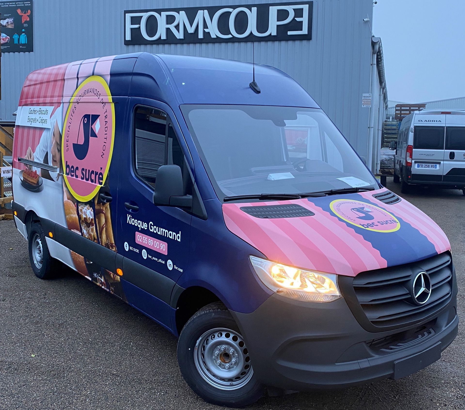 Un trophée en or flanqué de deux bouteilles de vin mousseux et de deux trophées en forme de coq Vainqueur 2016 sur une table de marque.