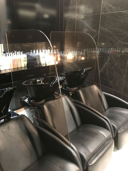 Éléments de vitrage entre des sièges d'un salon de coiffure