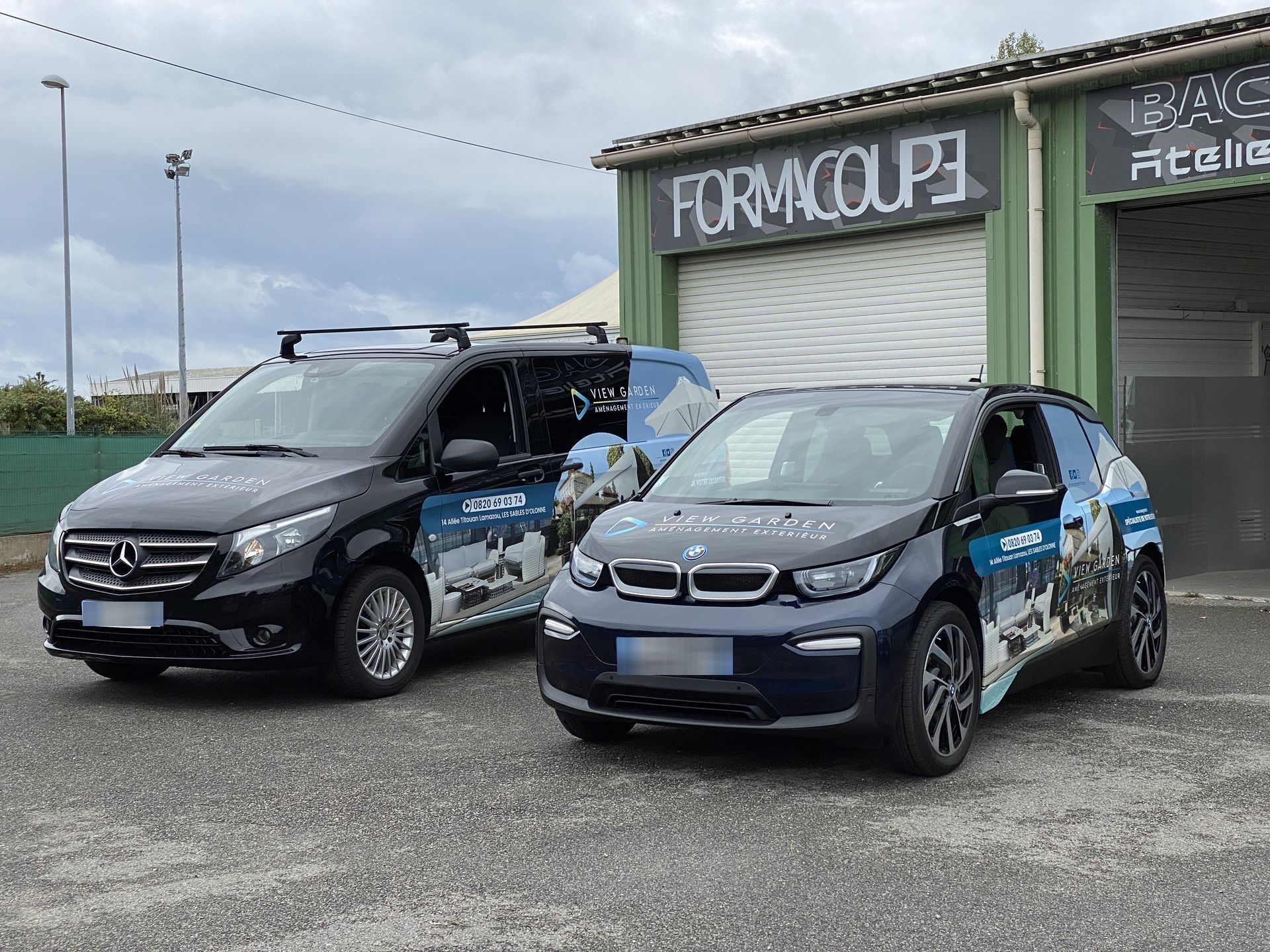 Deux voitures de société aux couleurs de la marque sont garées devant un bâtiment FMC Formacoupe, sur un terrain gravillonné, sous un ciel nuageux.