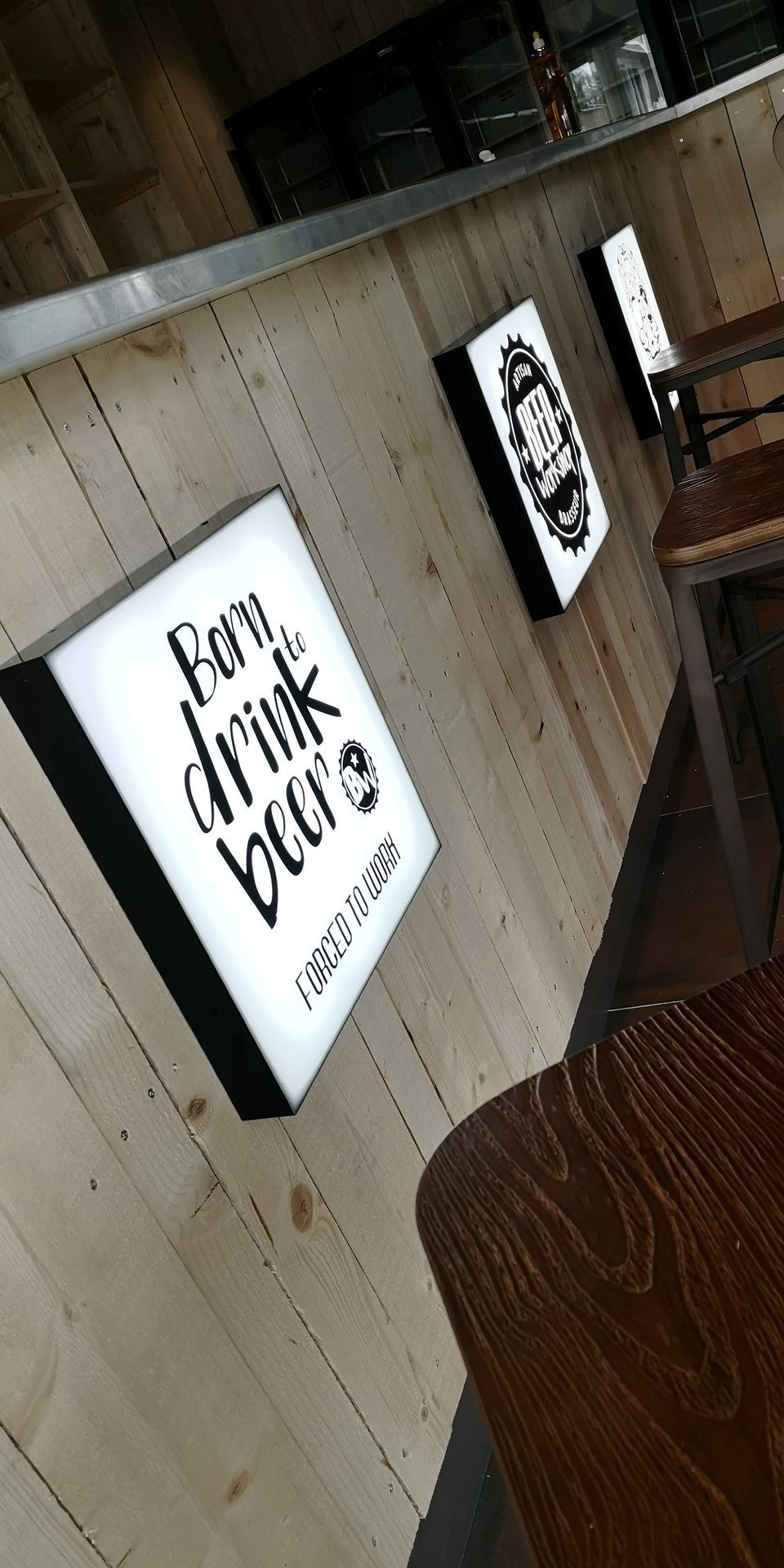 Deux enseignes lumineuses sur un mur en bois d'un bar.