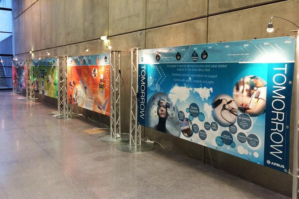 Couloir d'exposition d'art avec des panneaux muraux colorés, dont un grand panneau bleu DEMAIN.