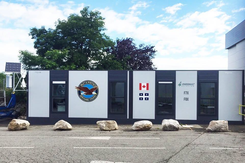 Panneau extérieur à plusieurs panneaux et drapeau canadien, installé en bordure de route avec arbres et rochers.
