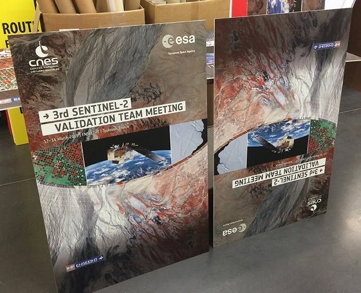 Deux affiches colorées de l'ESA sur une table, faisant la promotion de la 3e réunion de l'équipe de validation de Sentinel-2.