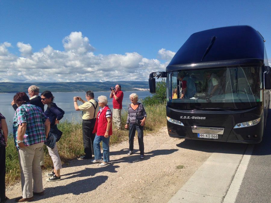 Eine Gruppe von Menschen steht vor einem Doppeldeckerbus.