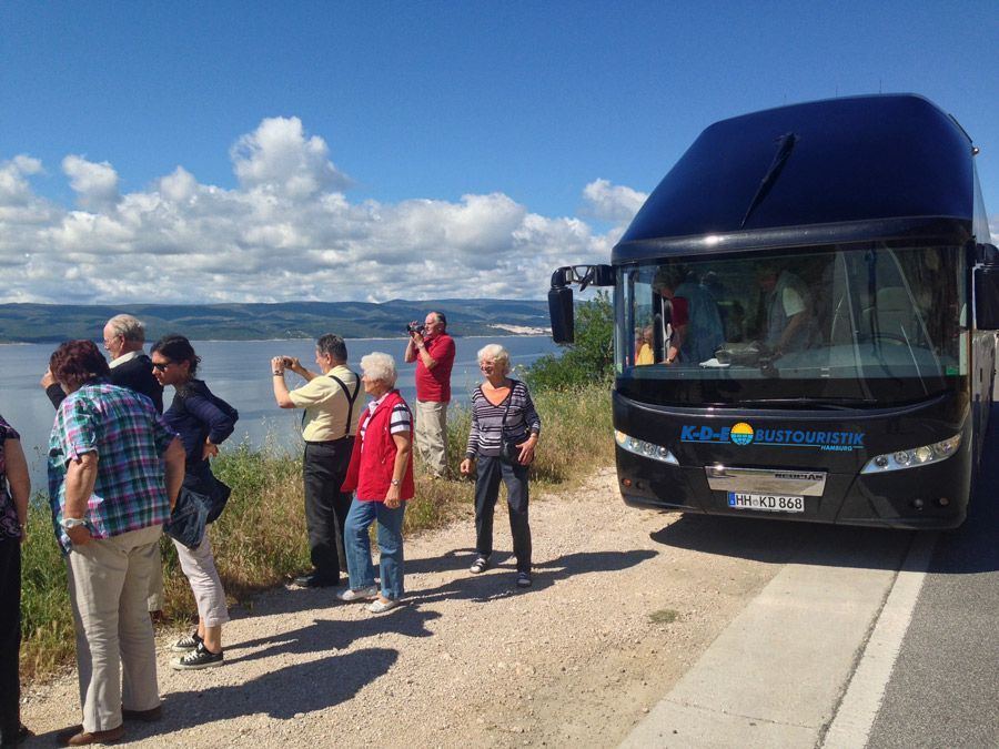 Eine Gruppe von Menschen steht vor einem blauen Bus