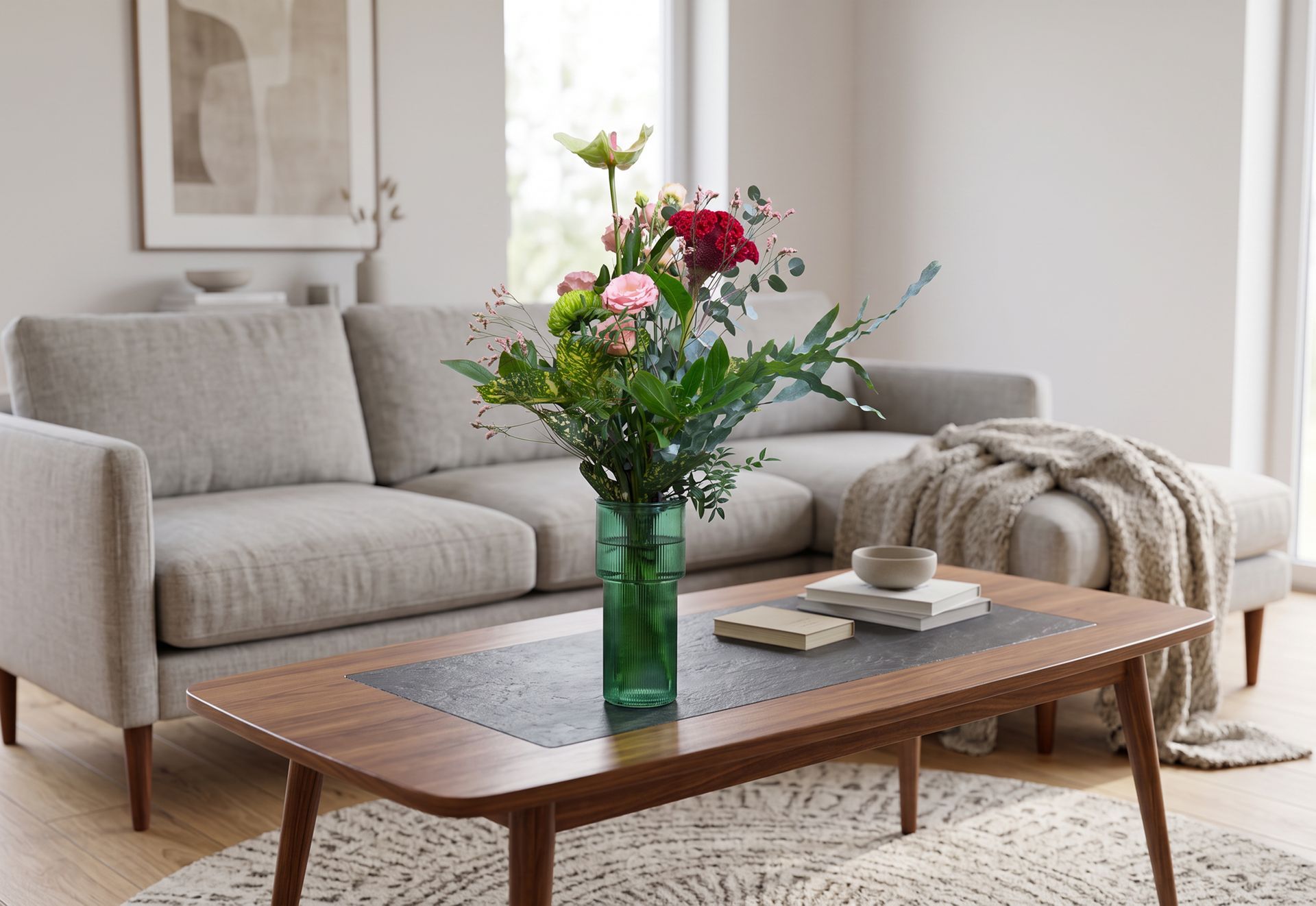 Helles Wohnzimmer mit grauem Sofa, hölzernem Couchtisch und einer Vase mit bunten Blumen.
