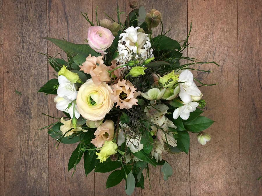 Pastellfarbener Blumenstrauß mit weißen, cremefarbenen, rosa und grünen Blüten auf Holzgrund