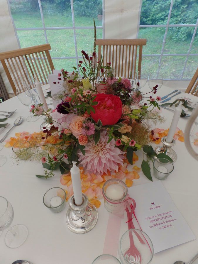 Elegantes Blumengesteck mit Kerzen auf einem weißen Tisch bei einem formellen Treffen