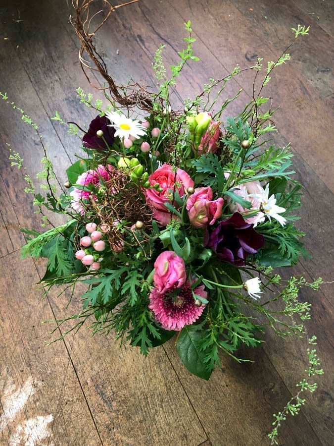 Ein rosa-lila Blumenstrauß mit Grünzeug auf einem rustikalen Holzboden