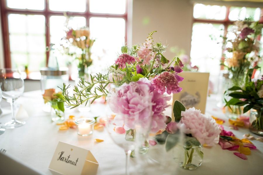Elegante florale Tischdekorationen mit rosa und lila Blüten auf einem hellen Esstisch