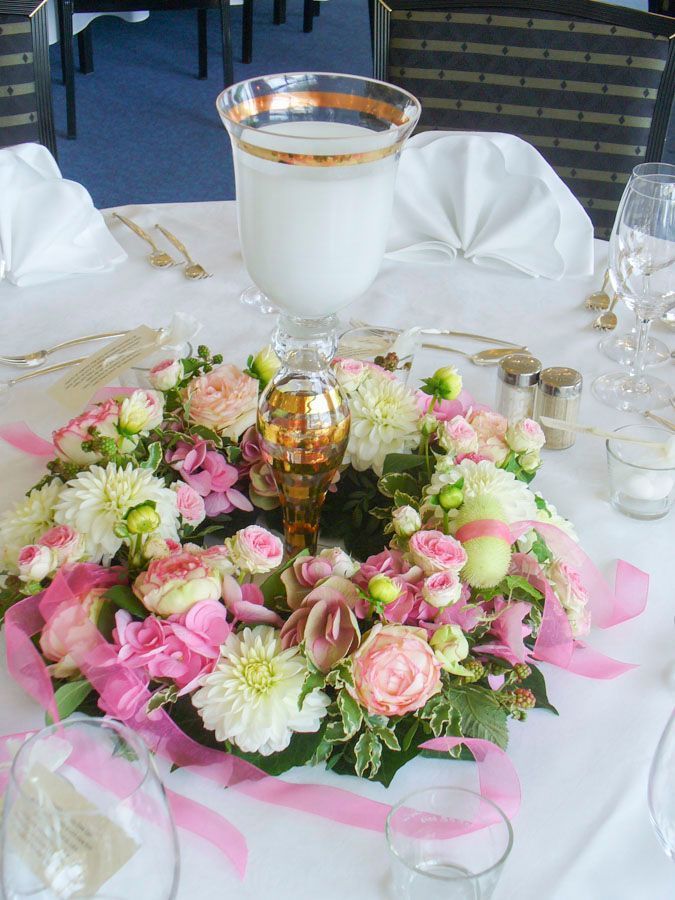 Ein rosa-weißes Blumengesteck mit Kerzen auf einem für das Essen im Freien gedeckten Tisch