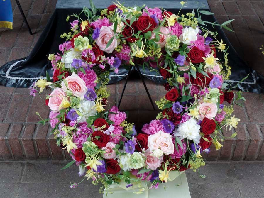 Ein farbenfroher Blumenkranz aus rosa, weißen, violetten und roten Blüten auf einem Backsteinsims.