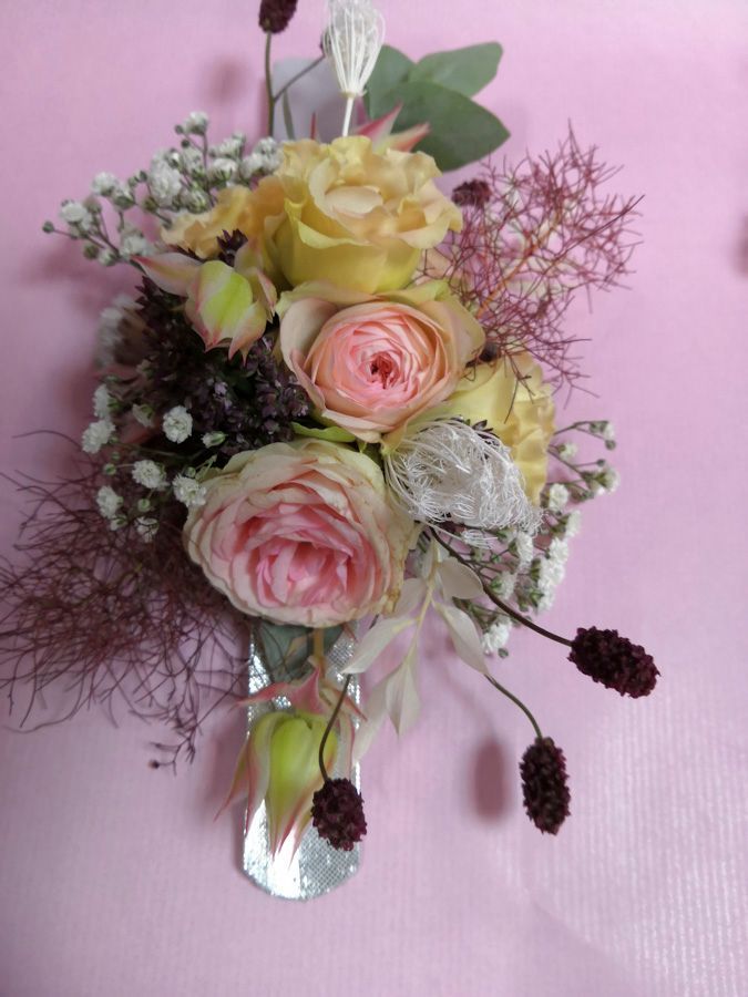 Pastellrosa und gelber Blumenstrauß mit zartem Grün vor einem sanftrosa Hintergrund