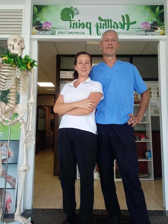 Un hombre y una mujer de pie frente a un cartel que dice 