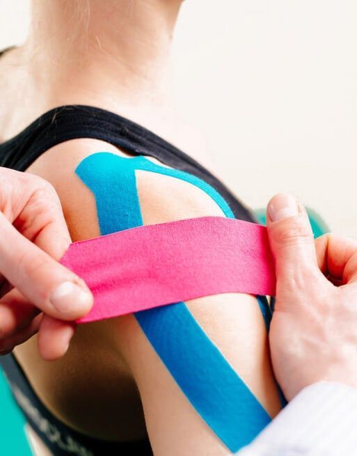 Una persona está colocando cinta kinesiológica en el hombro de una mujer.