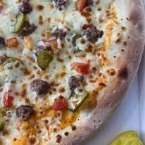 Gros plan d'une pizza avec des garnitures comprenant des tomates, de la viande et des poivrons verts.