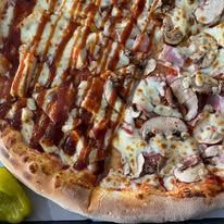 Gros plan d'une pizza en deux moitiés : l'une avec sauce barbecue, l'autre avec champignons et autres garnitures.