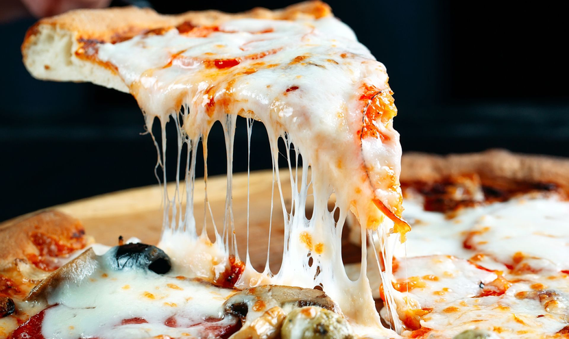 Tranche de pizza avec du fromage fondu soulevé de la tarte, dans un plateau en bois.