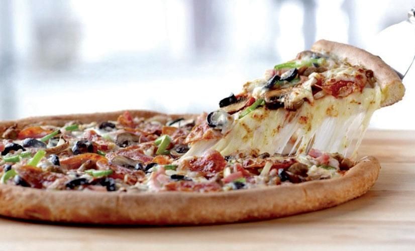 Pizza garnie de pepperoni, d'olives et de poivrons verts. Une part est coupée.