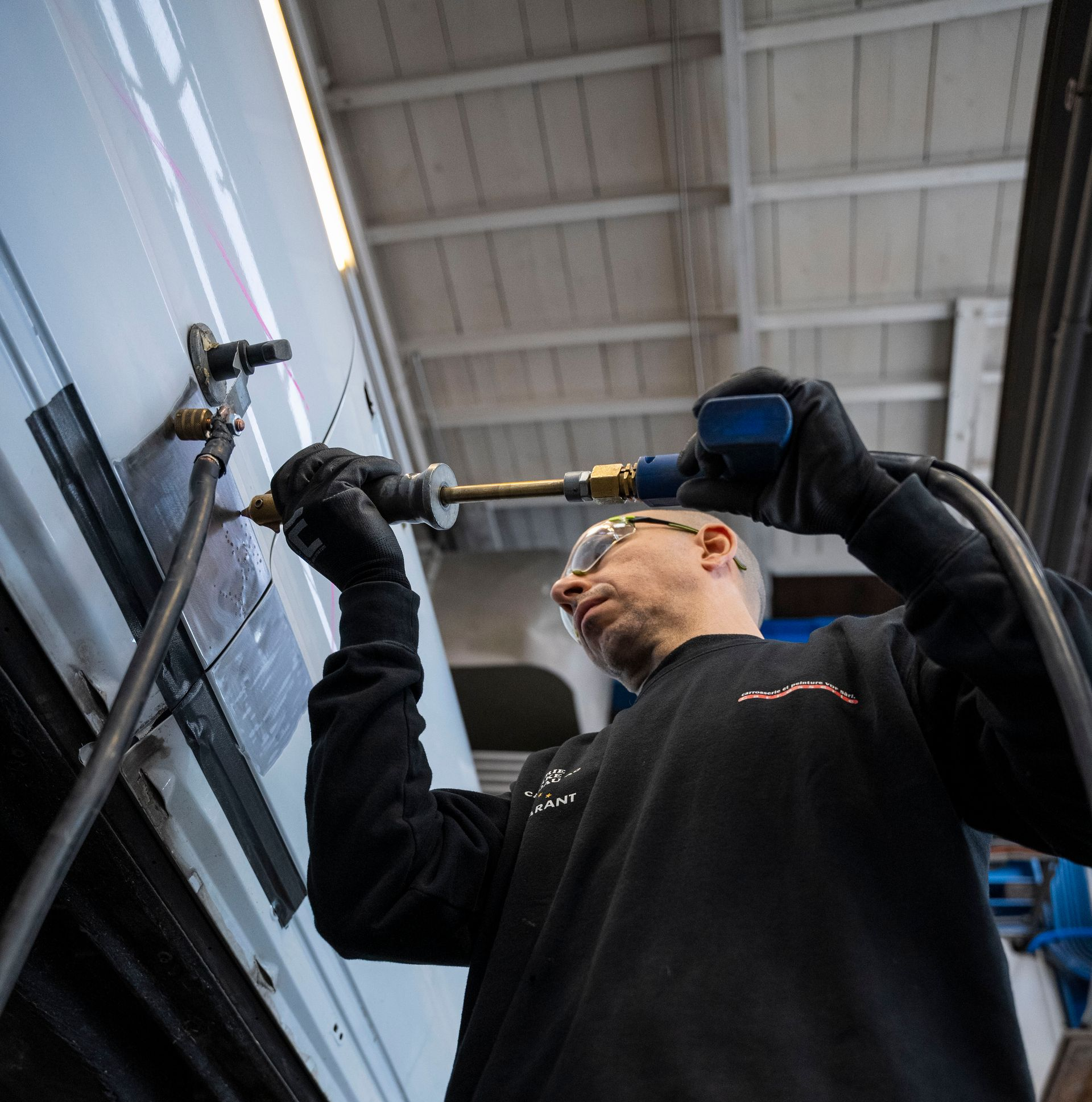 Eine Person im Schutzanzug bedient eine Maschine in einer sterilen Umgebung und ist an ein Beatmungsgerät angeschlossen.
