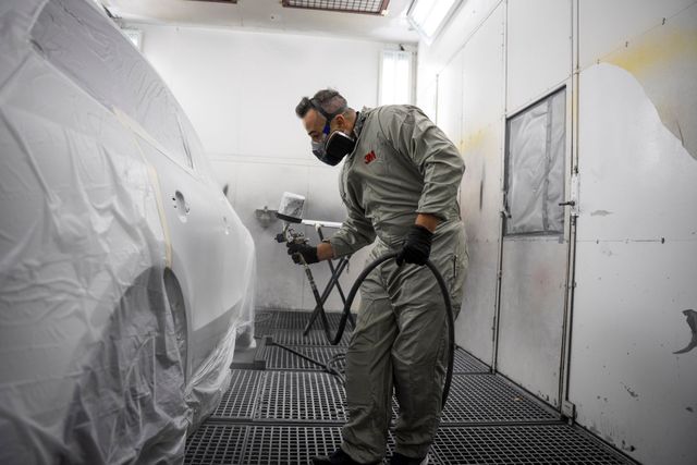 Eine Person im Schutzanzug bedient eine Maschine in einer sterilen Umgebung und ist an ein Beatmungsgerät angeschlossen.