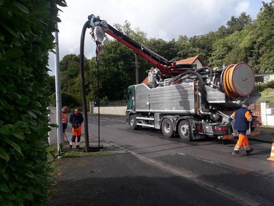 Un camion de curage stationné dans une rue avec des ouvriers autour.