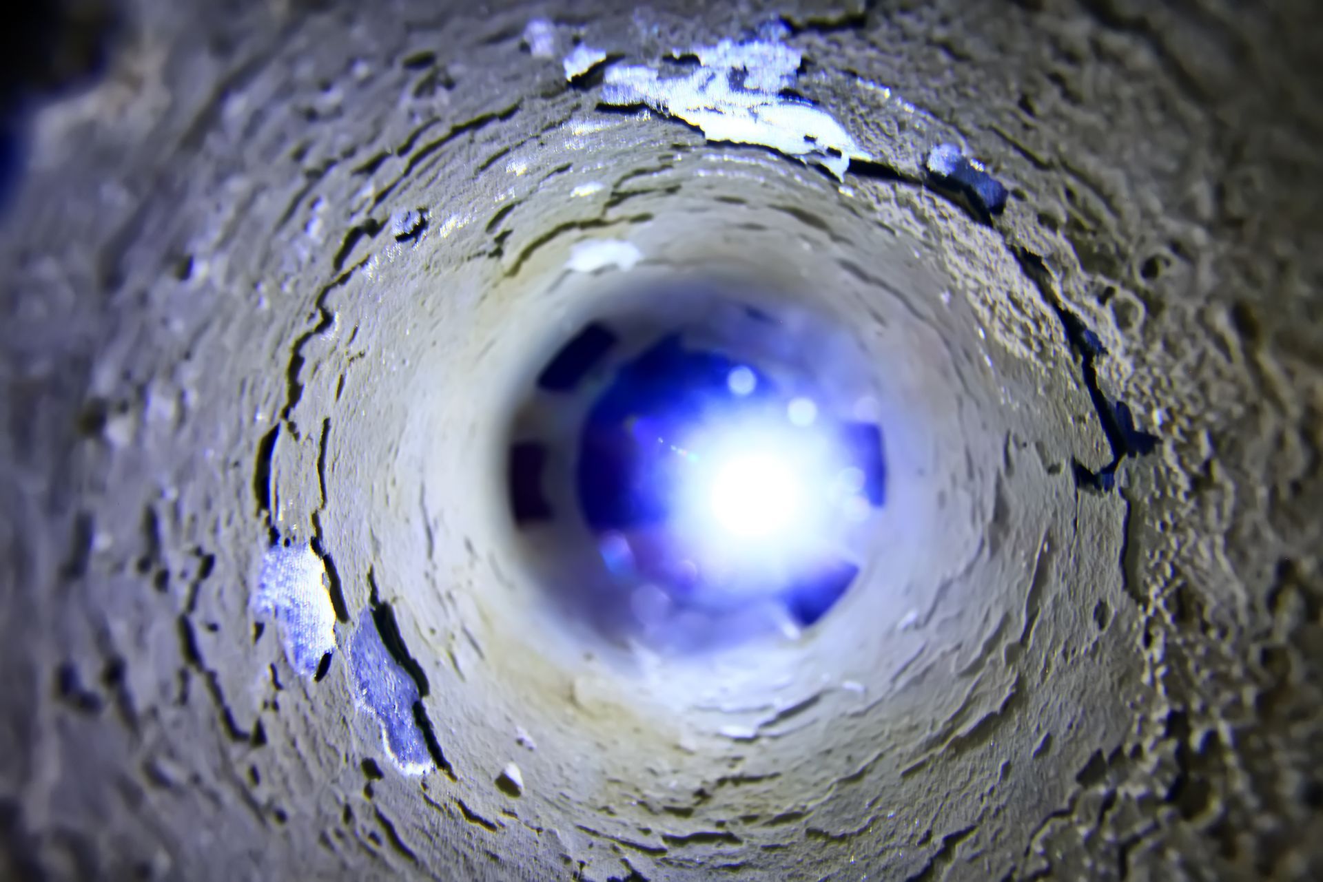 À l'intérieur d'un tuyau en béton brut, une lumière bleu blanc éclatante brille à l'extrémité opposée.