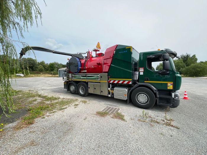 Camion avec bras d'aspiration relevé nettoyant la canalisation.