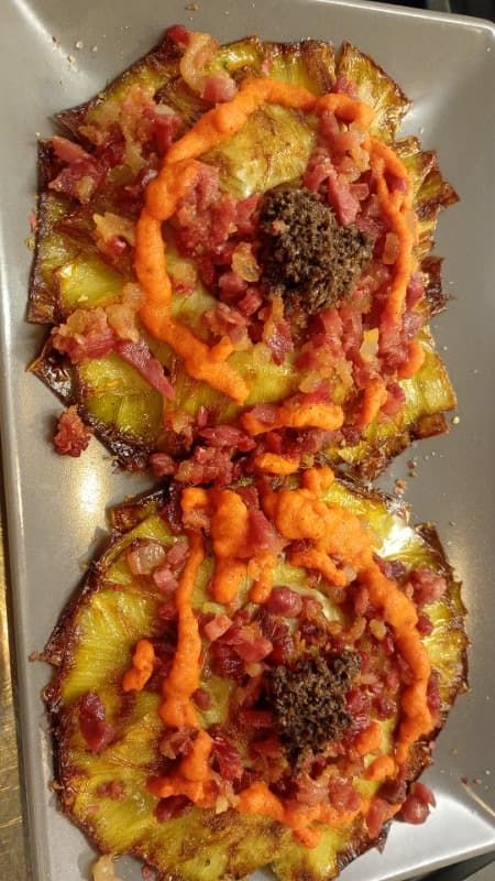 Dos pizzas con queso, cubiertas con salsa roja y carne desmenuzada en un plato.