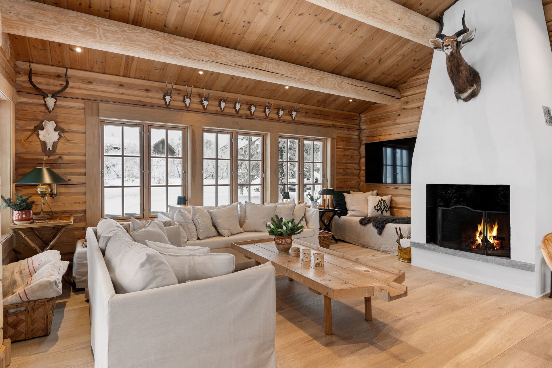 Rustic cabin living room with a fireplace, antlers, and a large white sofa.