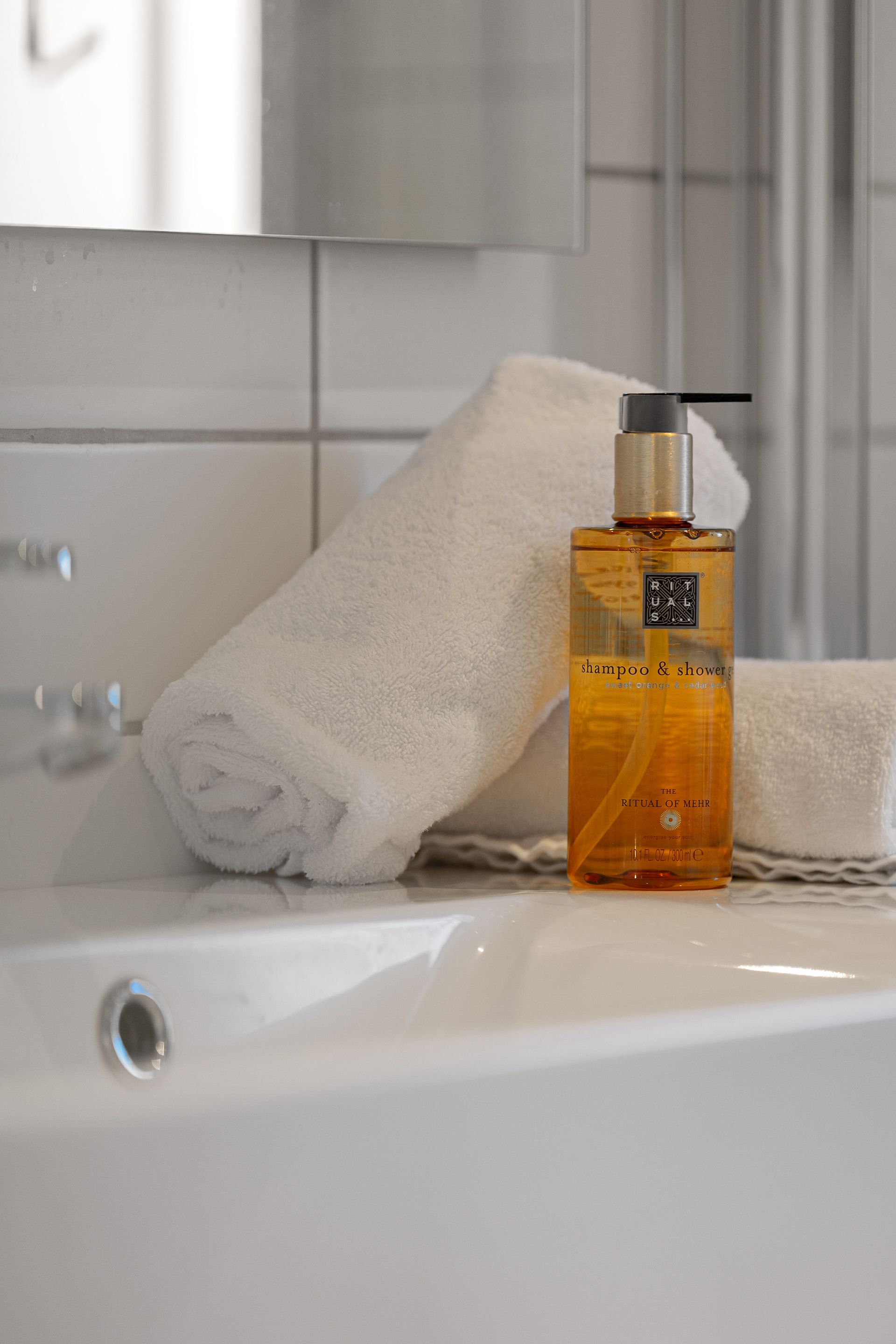 White towels and amber liquid soap on a bathroom sink.