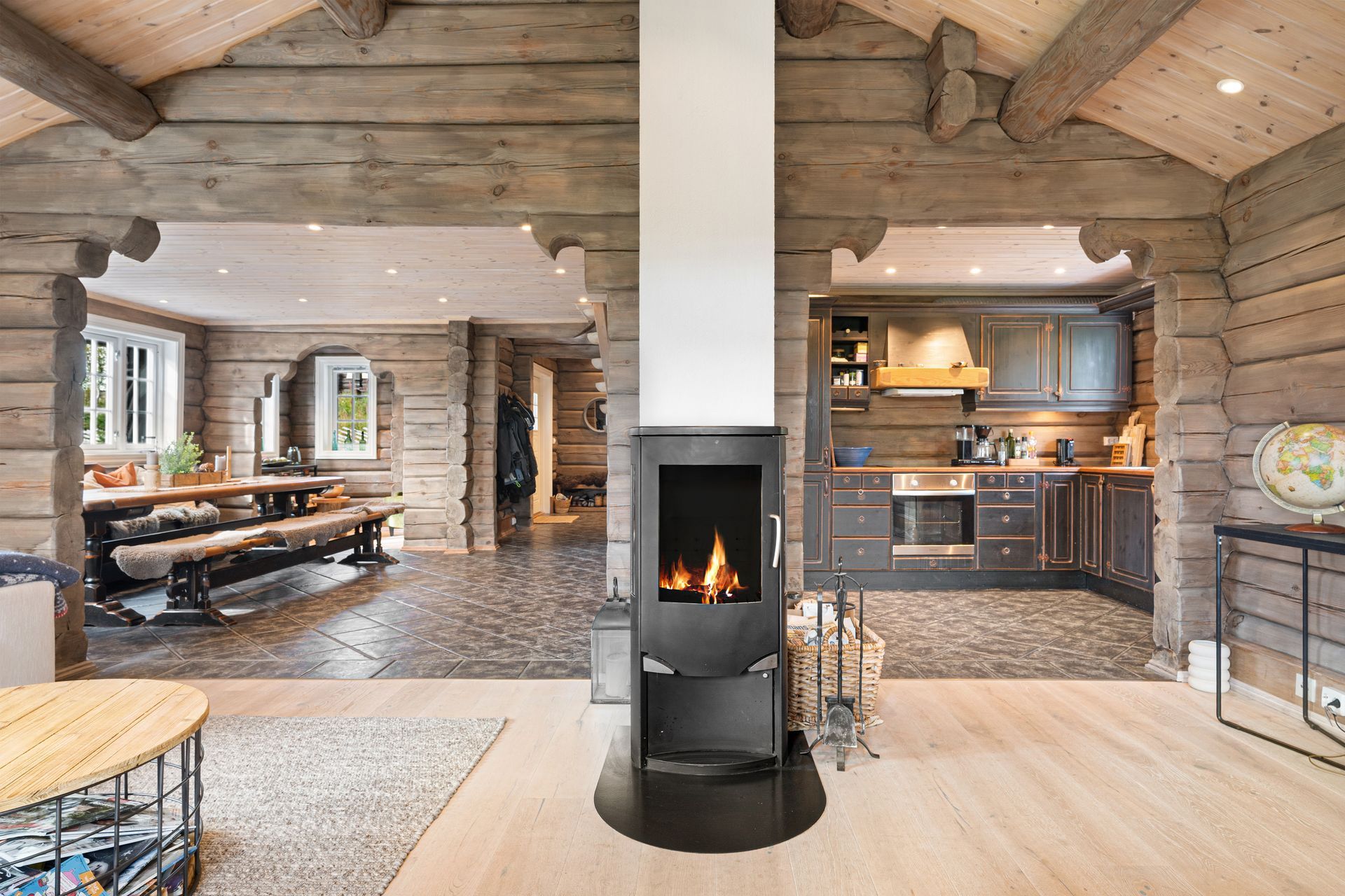 Rustic log cabin interior with a modern fireplace, kitchen, and dining area.