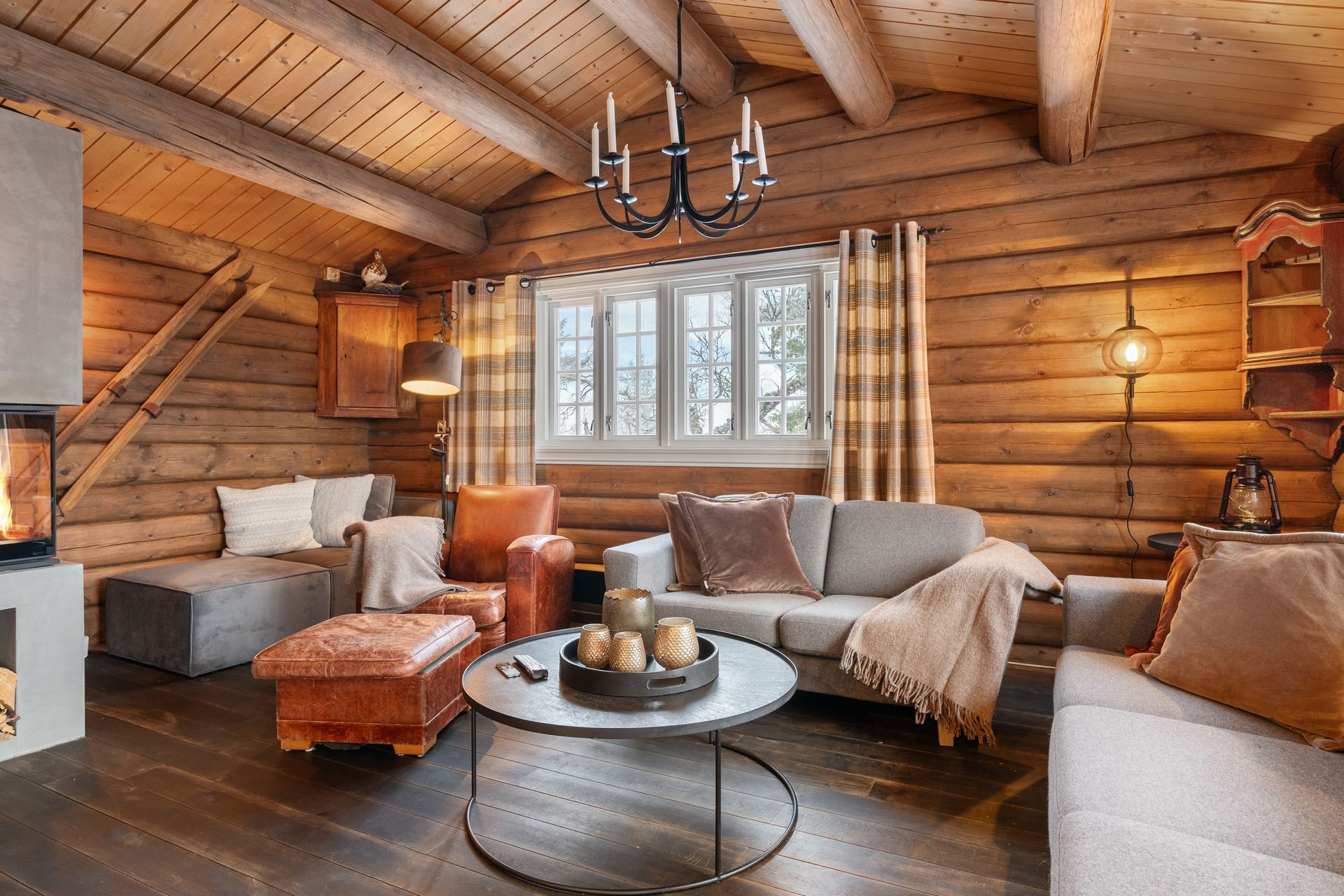 Cozy cabin living room with log walls, fireplace, and comfortable furniture bathed in warm light.