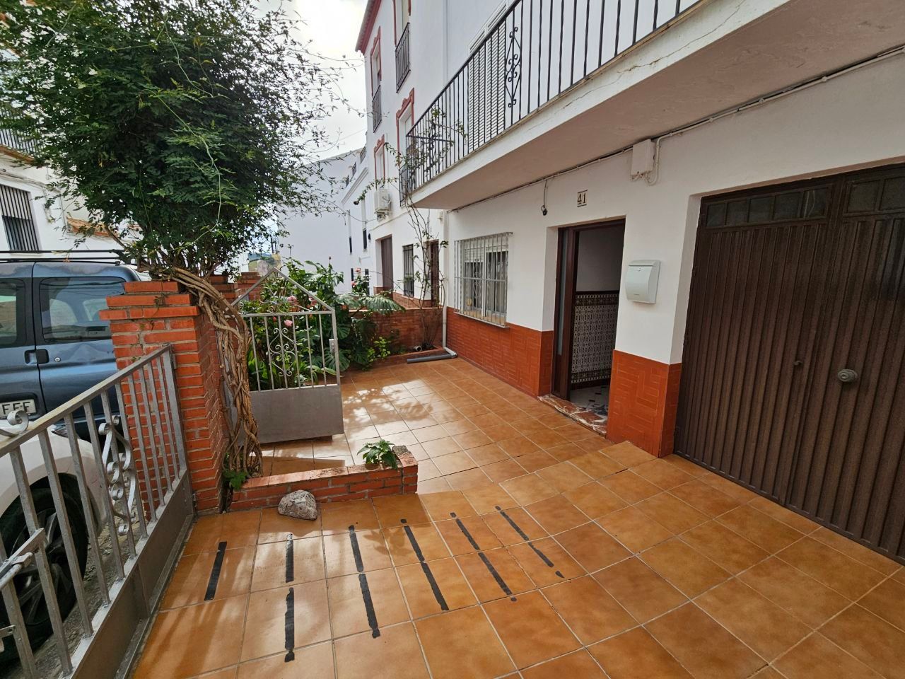 Vista exterior de un edificio con patio de baldosas, puerta y puerta de garaje.