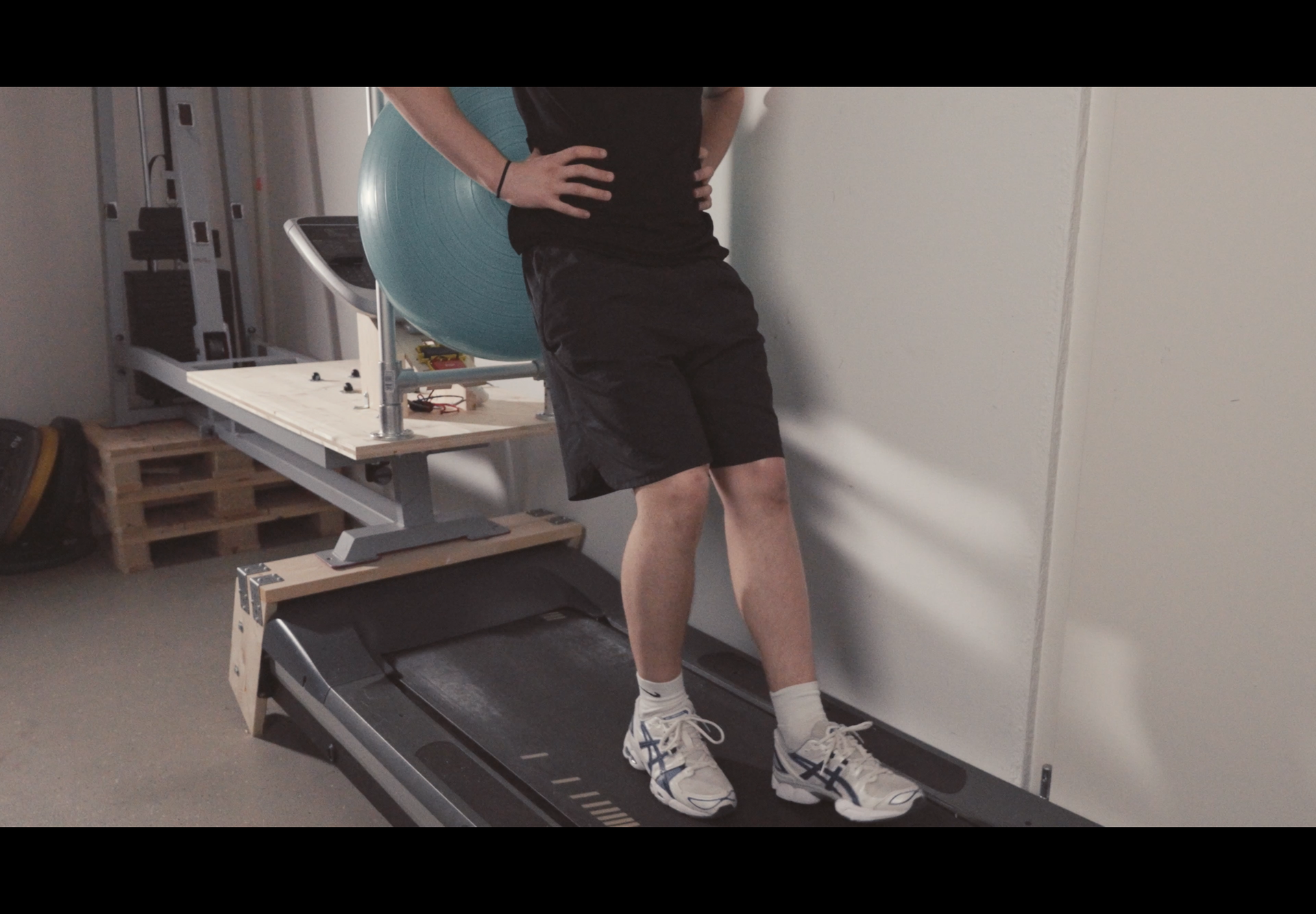 Ein Mann steht mit den Händen in den Hüften auf einem Laufband.