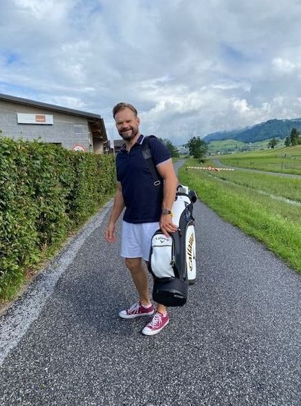 Ein Mann trägt eine Golftasche eine Straße entlang.