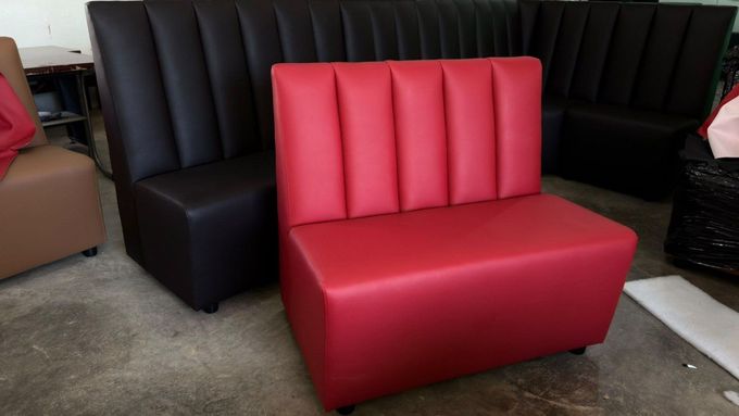 Asiento corrido tapizado en rojo, delante de otro negro, sobre suelo enmoquetado