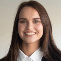 A woman in a suit and white shirt is smiling for the camera.