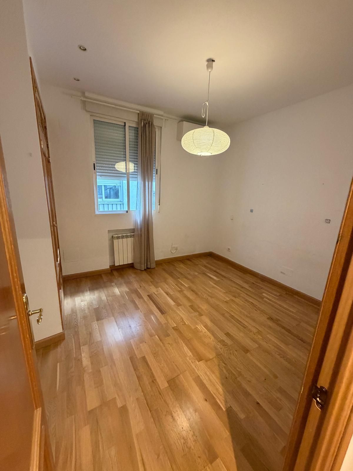 Habitación en renovación con muebles cubiertos de plástico. Materiales de pintura sobre una mesa.