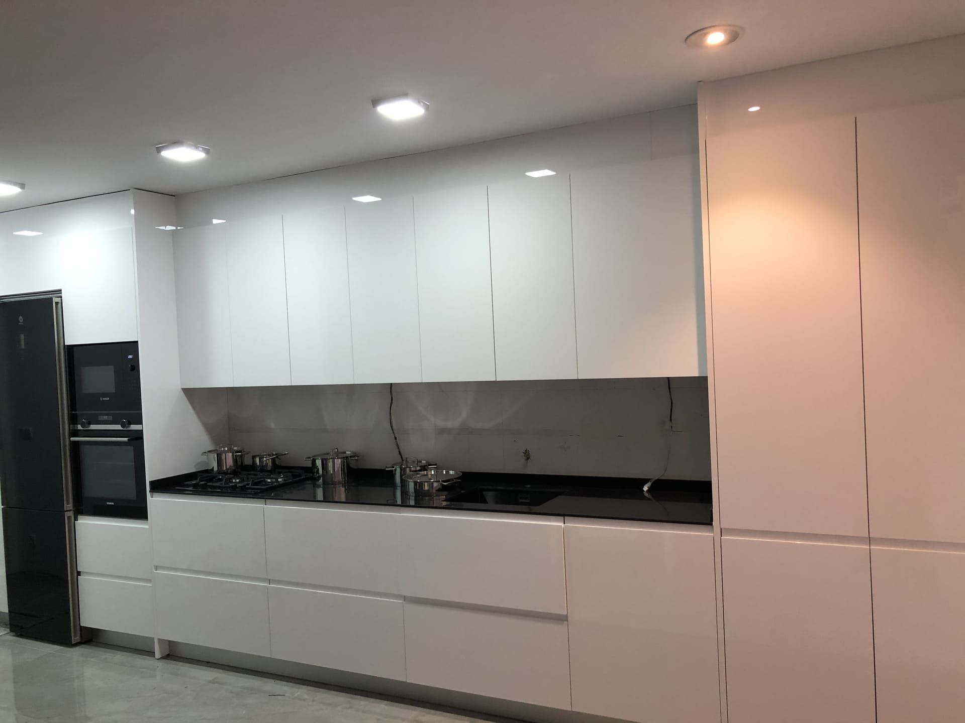 Cocina moderna completamente blanca con electrodomésticos de acero inoxidable y encimera negra.