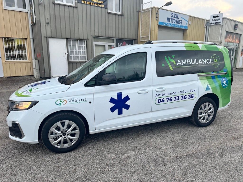 Ambulance blanche adaptée aux PMR, garée devant un bâtiment.