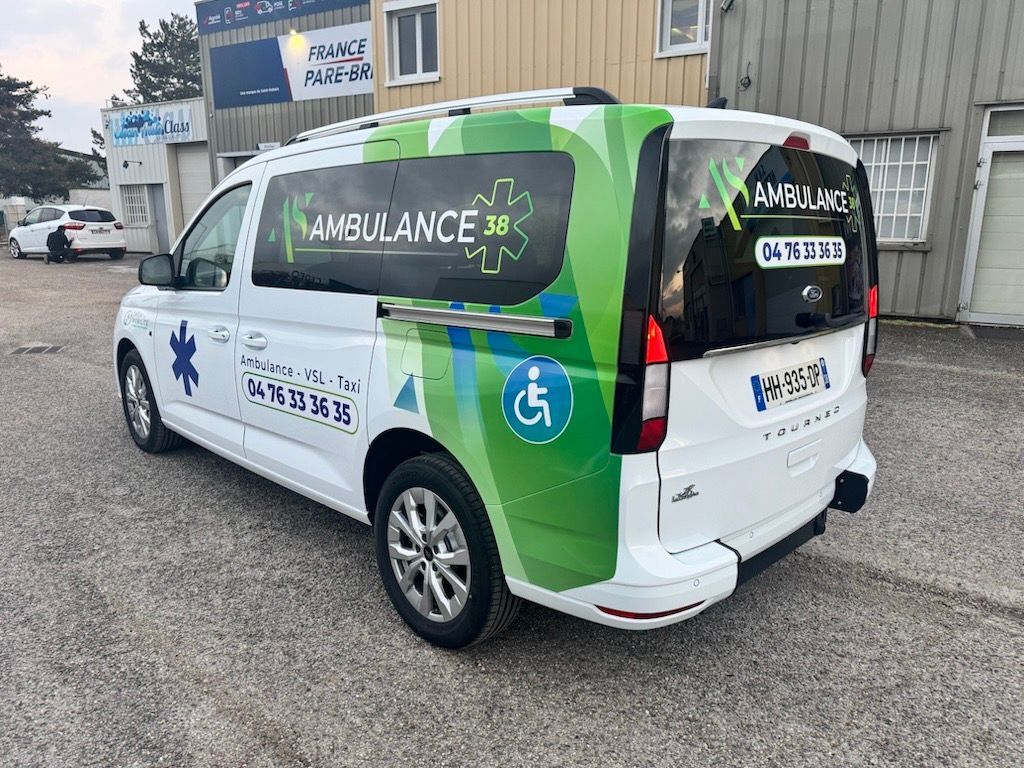 Ambulance blanche, stationnée à l'extérieur, affichant le symbole d'accessibilité et les coordonnées.