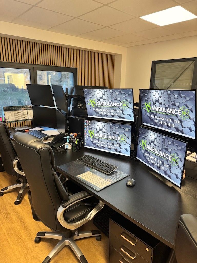 Un espace de travail de bureau moderne avec deux configurations de bureaux, chacune comprenant plusieurs écrans d'ordinateur, des chaises noires et des bureaux sombres.